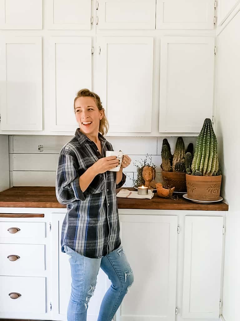 woman holding coffee mug standing in front of farmhouse butlers pantry countertop and cabinets