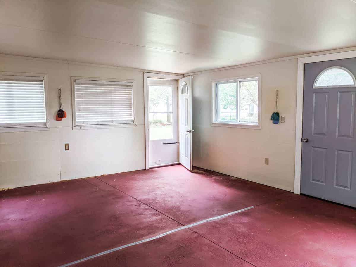 large farmhouse room with two exterior doors three windows and bare floors