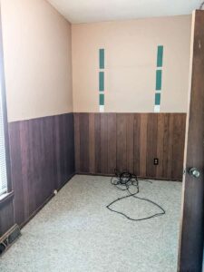farmhouse laundry room prior to remodel with wood panel walls and carpet