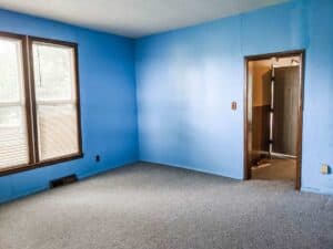 farmhouse bedroom with blue painted walls and carpeted floors prior to remodel