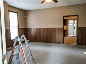 farmhouse living room with wood panel walls and carpet