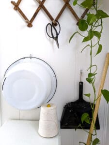 farmhouse mudroom with large wash basin spool of twine broom dustpan pothos plant and garden sheers
