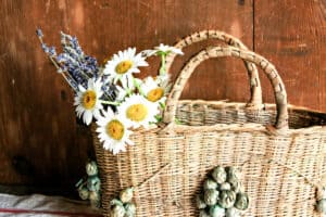 woven basket filled with daisies and lavender against a wooded wall backdrop