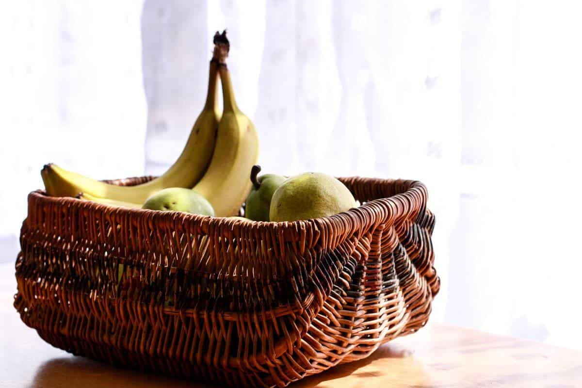 brown vintage basket filled with bananas and pears sitting on a table