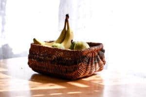 brown vintage basket filled with bananas and pears sitting on a table