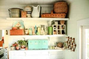 white shelves in laundry room filled with vintage baskets pitchers potted plants and glass jars