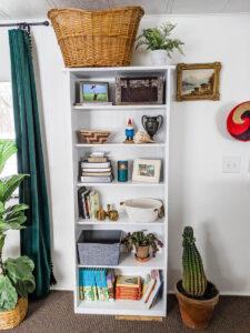 white bookshelf with plants baskets and books