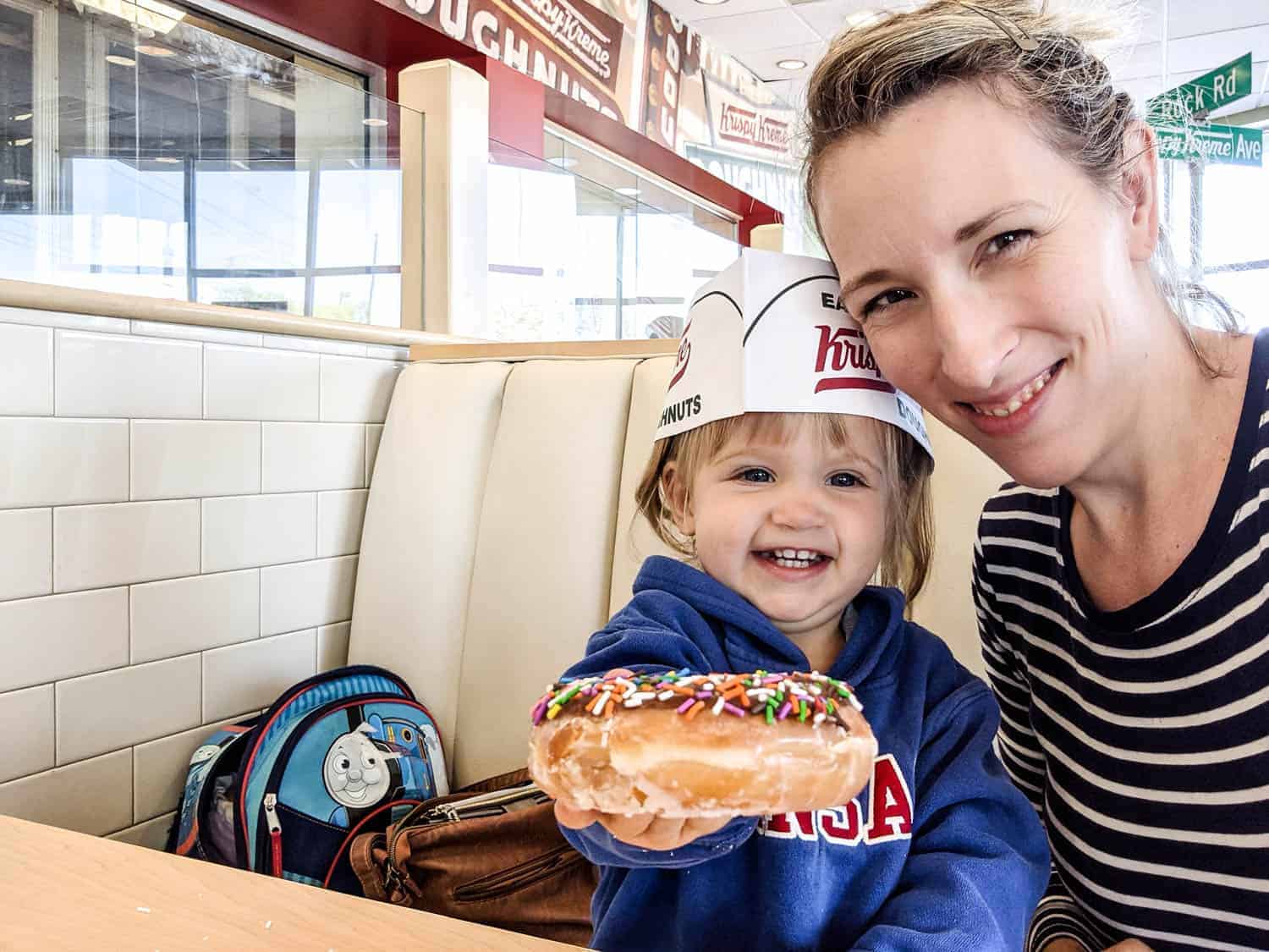 a mother and her little girl sharing a krispy kreme donut while out garage saleing