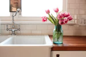 glass vase of pink tulips sitting on kitchen counter next to a farmhouse sink