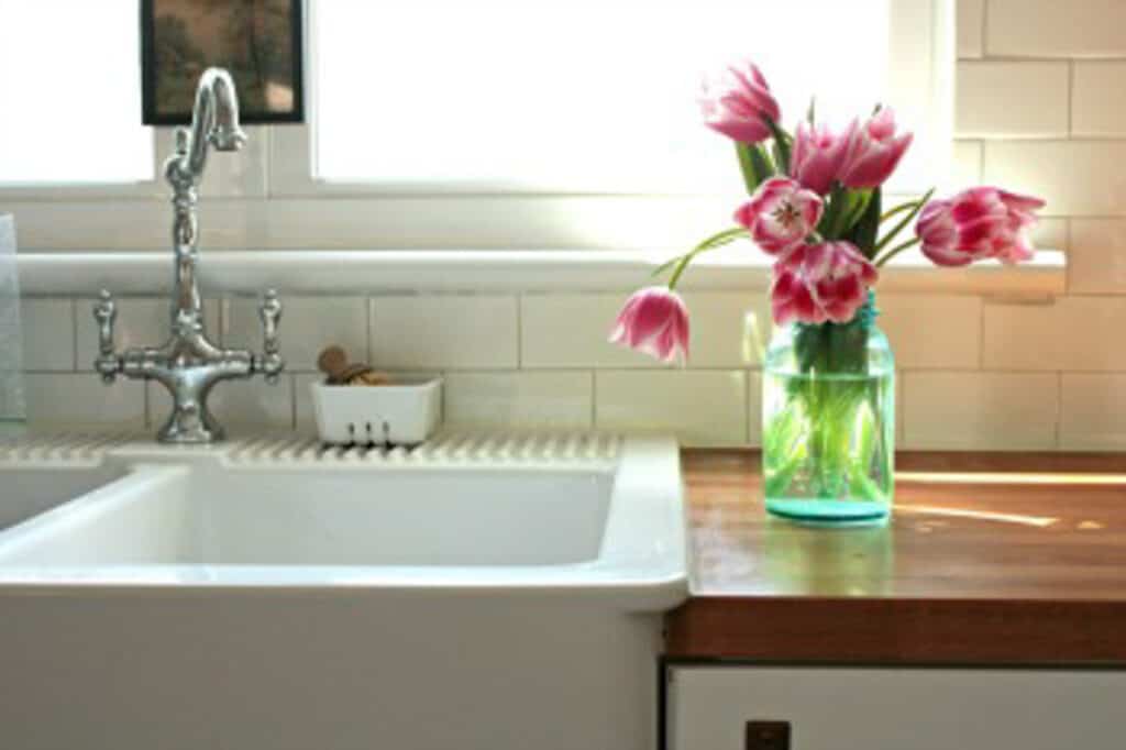 glass vase of pink tulips sitting on kitchen counter next to a farmhouse sink