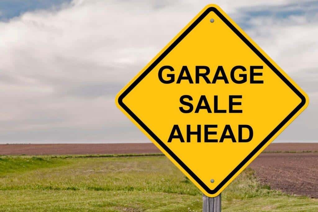 yellow garage sale sign with field in background