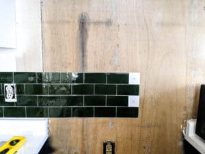 installing dark green sticky tile as a kitchen backsplash over plywood