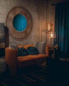 boho living room with ambient lighting orange couch and round mirror hanging on wall
