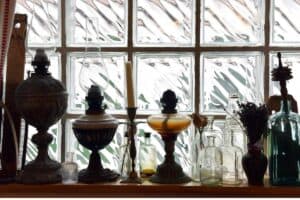 vintage oil lamps and glass apothecary jars lined up in glass block window