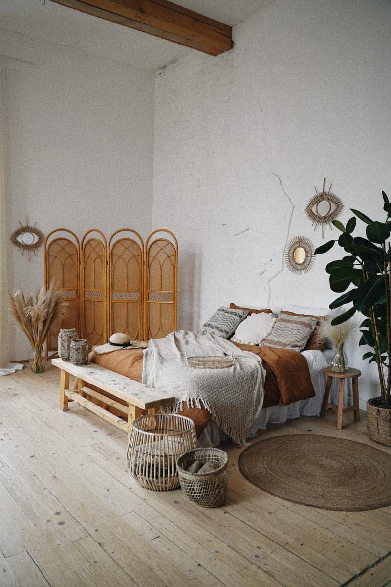 boho bedroom with low platform bed layers of blankets neutral walls woven baskets