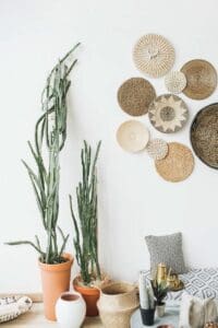 vintage style boho living room with native baskets hanging on wall floor pillows and potted cacti