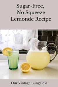glass pitcher of homemade lemonade with half lemon and glass of lemonade sitting on kitchen counter