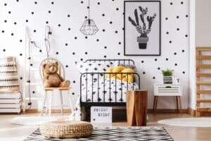 bedroom of child with polka dot wallpaper black metal bed frame stuffed bear on wooden chair and rug