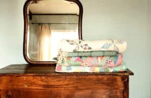 weathered farmhouse dresser with a mirror and stack of vintage quilts