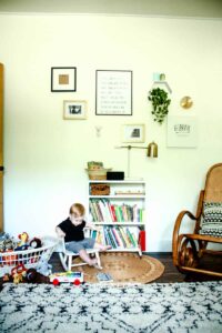 mid century nursery after remodel with toddler boy sitting in rocking chair