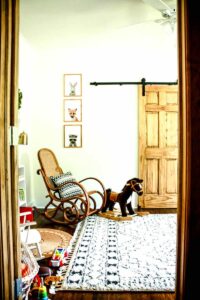 looking into mid century nursery with vintage rocking chair rocking horse and soft area rug