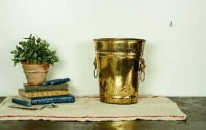 vintage gold bucket staged with linen towel stack of books and potted plant