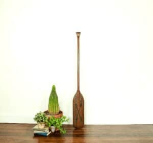 vintage wooden oar staged with potted plants and stack of books top selling item on etsy