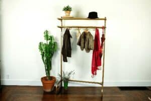 vintage coat rack full of coats scarves hat and umbrella staged with potted plants