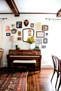 vintage rustic gallery wall above upright piano
