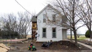exterior side view of farmhouse during renovation with unfinished foundation exposed walls