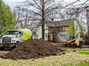 large mound of dirt and cement truck outside of farmhouse during renovation process