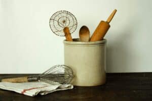 stoneware crock filled with vintage wooden cooking utensils