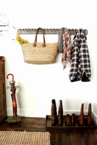 fall decoration setup of wooden coat rack with tote scarf coat and boot tray full of boots