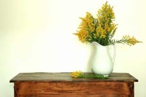 porcelain pitcher filled with goldenrod stems sitting on a vintage table fall decorations
