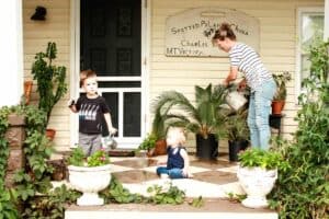 bungalow front porch design makeover reveal with mother son and daughter watering potted plants