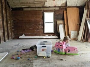 little girl plays with toys in the middle of a 1900s farmhouse room during renovation