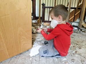 little boy holding screwdriver helping with renovations on 1900s farmhouse