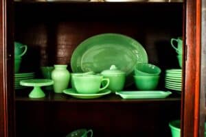 authentic vintage jadeite dishes stacked and displayed in wooden china cabinet