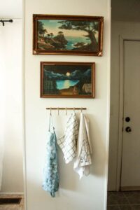 vintage framed paintings hanging above towel rack in mobile home kitchen