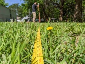 tape measure laying in grass to measure distance between clothesline poles