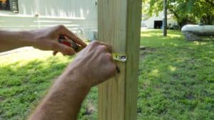 measuring and marking the spot on the post where a clothesline will be mounted