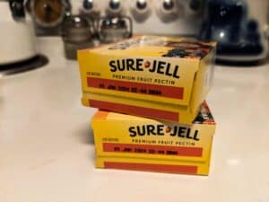 two boxes of sure jell premium fruit pectin on kitchen stove during canning process of peach butter