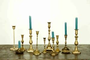 collection of twelve vintage brass candlesticks in varying heights with five teal candles