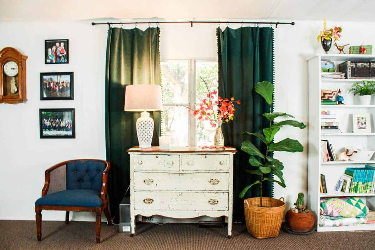 mobile home living room with farmhouse dresser bookshelf velvet curtains vintage chair and pictures