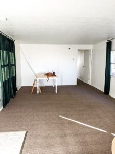 mobile home living room with white painted wall panels and green velvet curtains