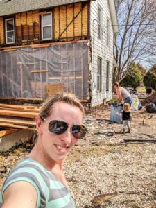 young family working outside of old farmhouse during deconstruction and renovation process