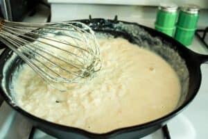 cast iron skillet filled with maple gravy frosting during cooking process