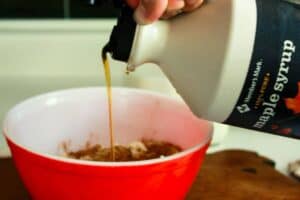 pouring maple syrup into mixing bowl of maple gravy frosting