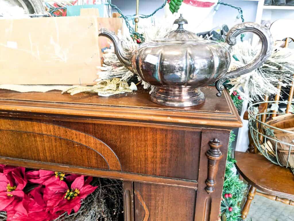 authentic vintage silver teapot sitting on wooden desk in thrift store