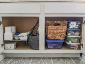 bathroom cabinet organized with baskets and plastic tubs